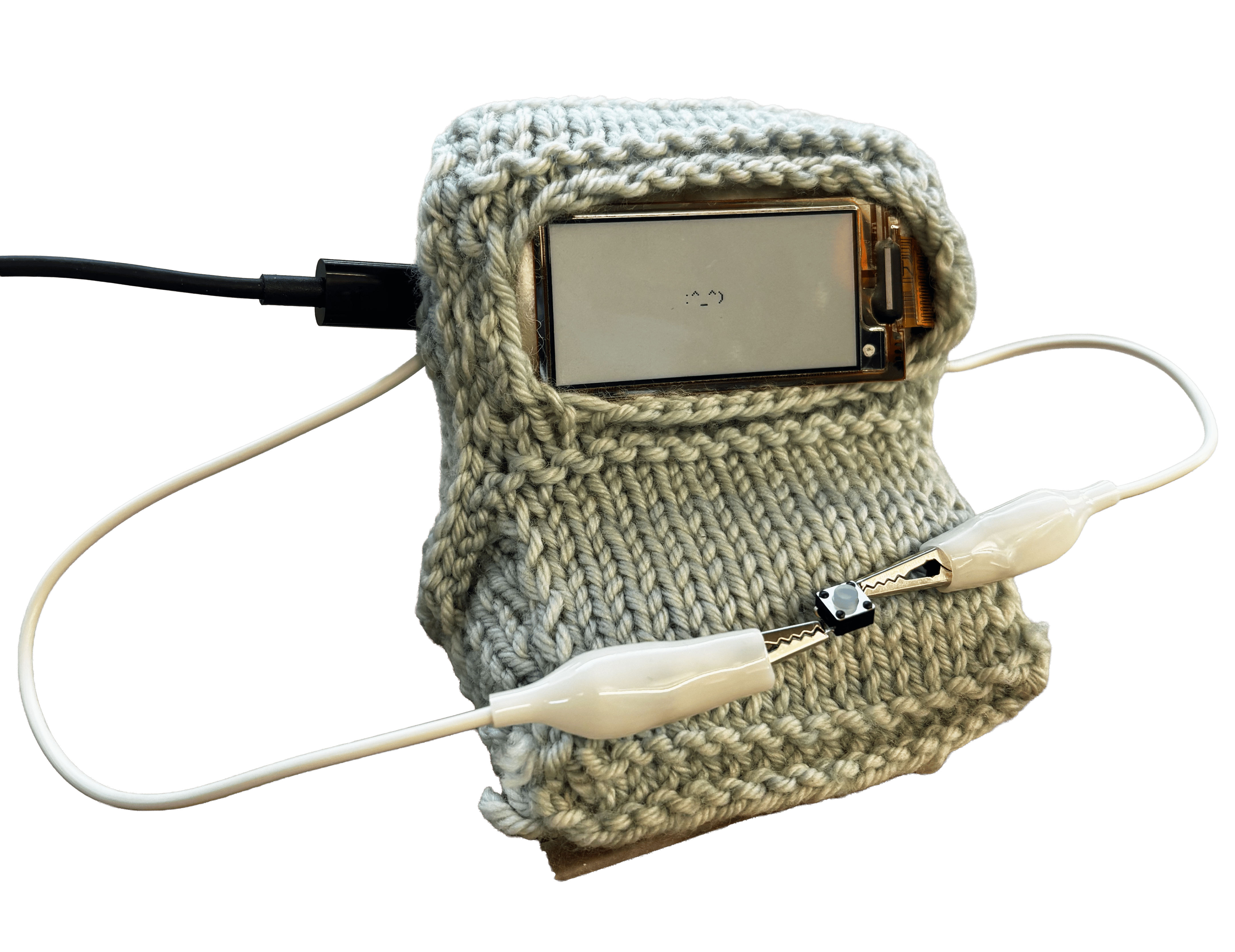 A finished tiny soft computer enclosure, hand-knit in soft grey yarn, with the eInk screen and a button on an alligator clip visible through the knit fabric.